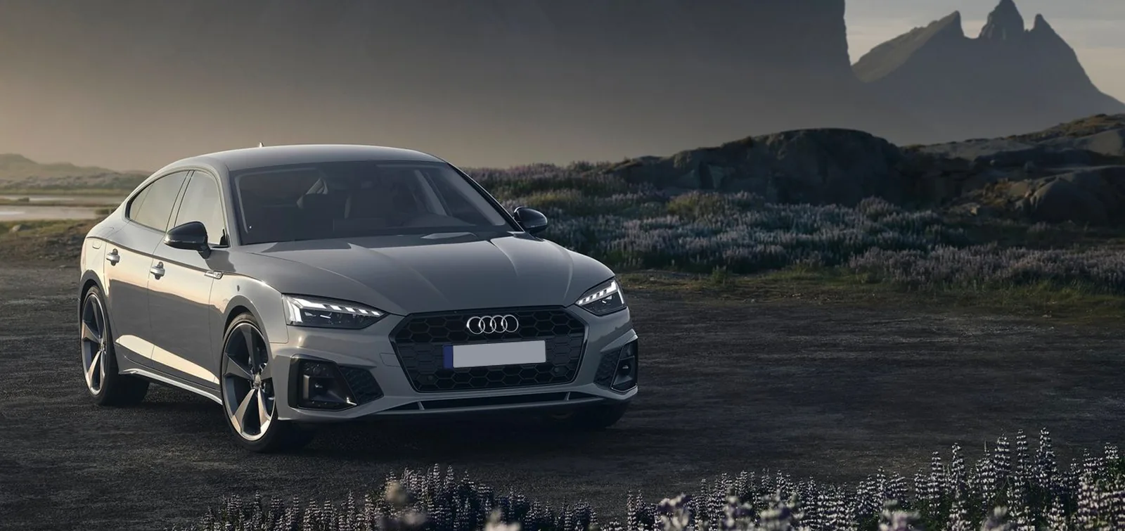 A silver executive saloon on an open road at dusk